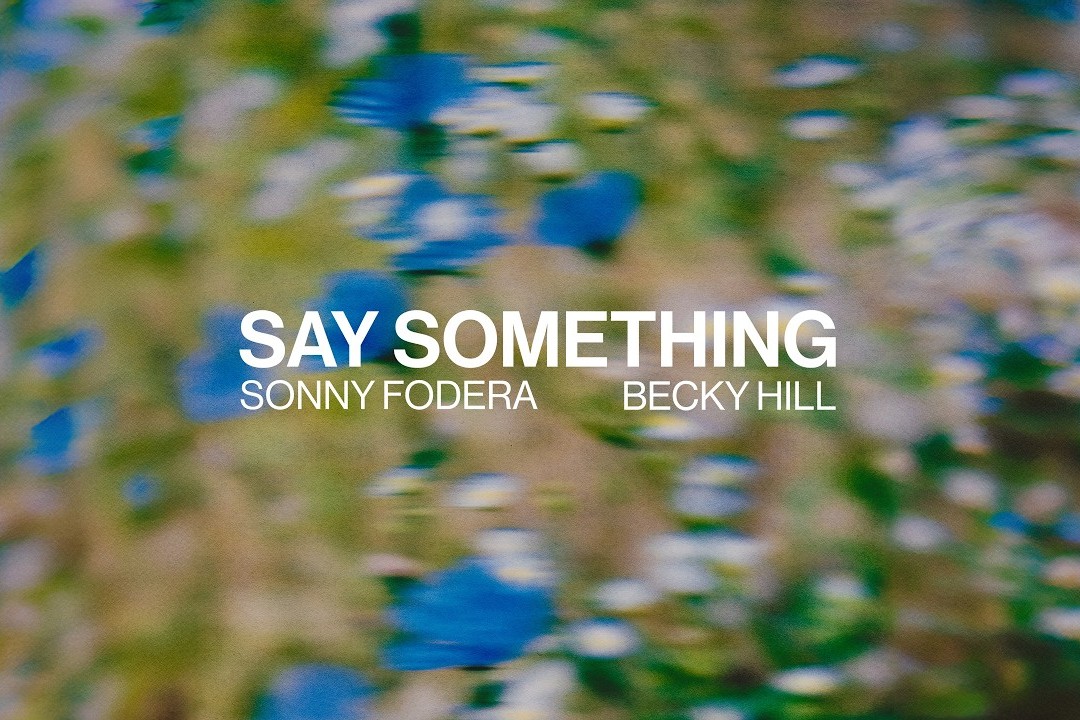 Say Something single artwork, blurred blue and green wildflowers with the title and the names Sonny Fodera and Becky Hill in white text