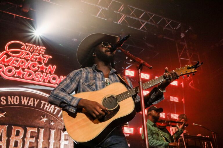 Shaboozey performing live with an acoustic guitar at The Great American Roadshow, November 2025