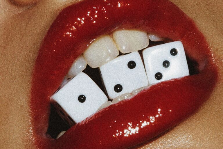 Cover art for James Hype and Volkoder single 1,2,3, an extreme close-up of a glossy red-lipsticked mouth biting three white dice showing one, two and three pips