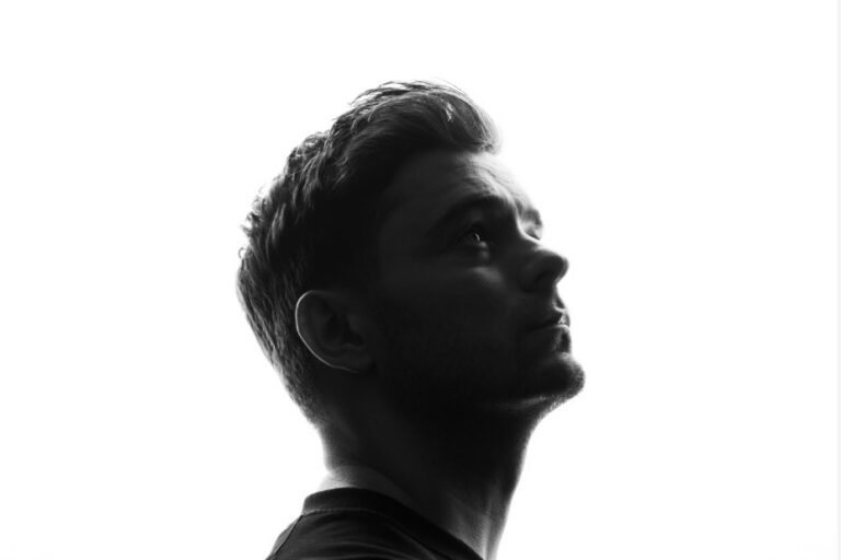 Black-and-white backlit silhouette of Martin Garrix in profile, looking upward against a bright white background