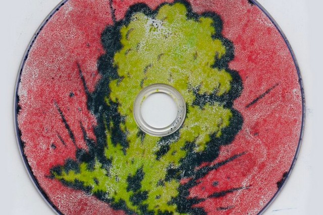 Shroom Clouds single cover art: a CD painted red with a yellow-green mushroom cloud outlined in black spreading across its face