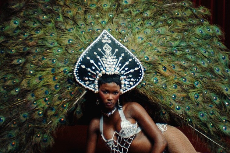 Every Night single cover art: a woman in a jewelled black-and-silver spade-shaped headdress and crystal-chain lingerie, lying on red velvet in front of a huge fan of peacock feathers