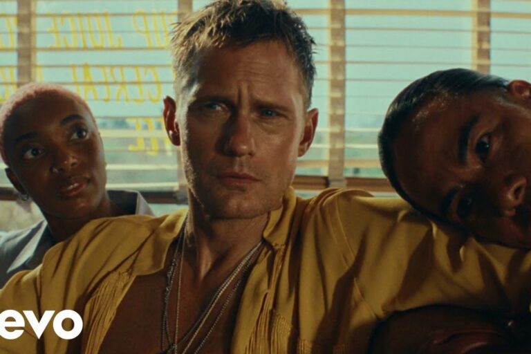 Alexander Skarsgård in an open mustard-yellow shirt and chain necklaces, flanked by two people in a sunlit diner booth with window blinds behind them, in a still from the Rolling Stones' Mr Charm video
